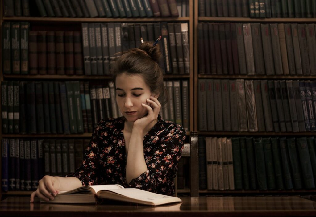 Learner reading at a table surrounded by books